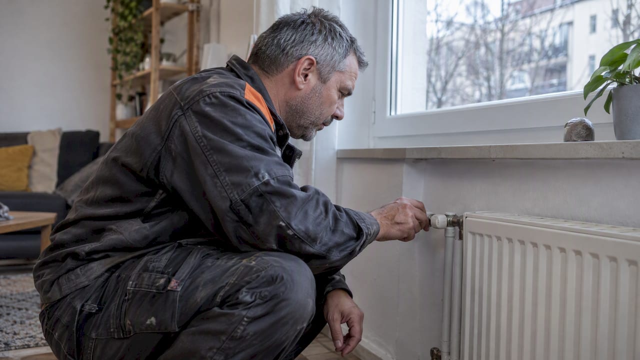 Technicien inspectant un radiateur défectueux dans un logement